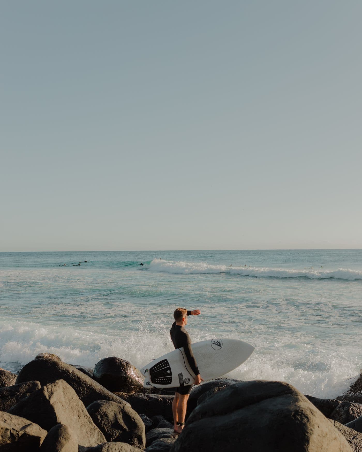 Surfer carrying a board beside the ocean